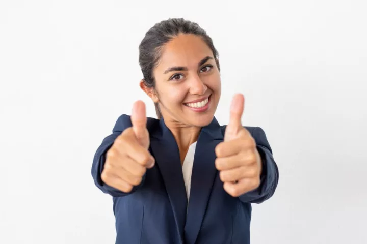 Une jeune femme d'affaires souriante en tailleur bleu marine faisant un double pouce en l'air