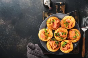 Yorkshire puddings salés garnis de saumon fumé et herbes fraîches sur assiette grise et planche rustique